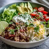 Colorful Low Carb Burrito Bowl with seasoned beef, cauliflower rice, avocado, and cheese.