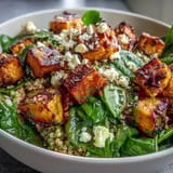 Presented in a ceramic bowl, this wholesome vegetarian meal showcases golden roasted vegetables and a garnish of pumpkin seeds.