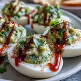 Bright green avocado filling piped into egg whites, finished with a zesty Sriracha kick and fresh cilantro.