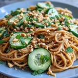 Refreshing Cold Peanut Sesame Noodles with Cucumber, drizzled with sauce.