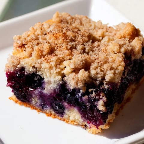 Warm Blueberry Buckle with golden, crumbly streusel topping, promising a sweet, comforting breakfast.
