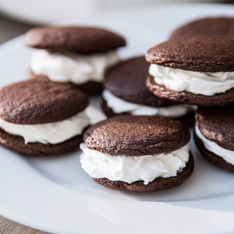 A plate stacked high with homemade Whoopie Pies, showcasing the fluffy vanilla cream spilling over the edges.