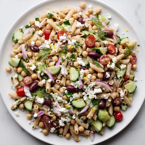 Enjoy a chilled serving of Lemon Herb Chickpea Pasta Salad, perfect for a light lunch or picnic.