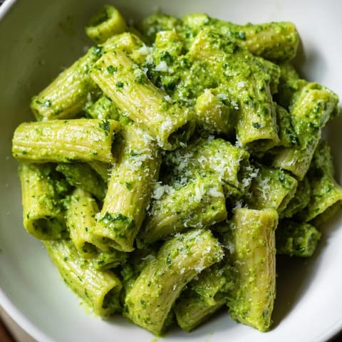 Creamy Avocado Pesto Mac served warm in a bowl, garnished with fresh basil and grated Parmesan for a vibrant, healthy twist on classic mac and cheese.