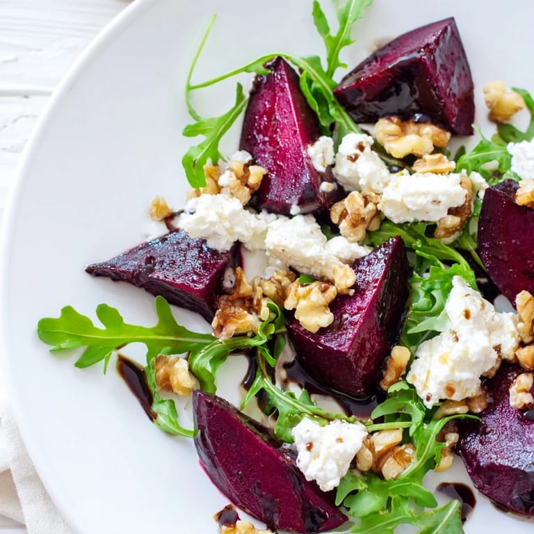 Close-up of Roasted Beet Goat Cheese Salad, sliced roasted beets and goat cheese atop peppery greens with toasted walnuts.