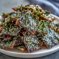 Crispy seaweed snack chips with sesame seeds and sea salt piled high.